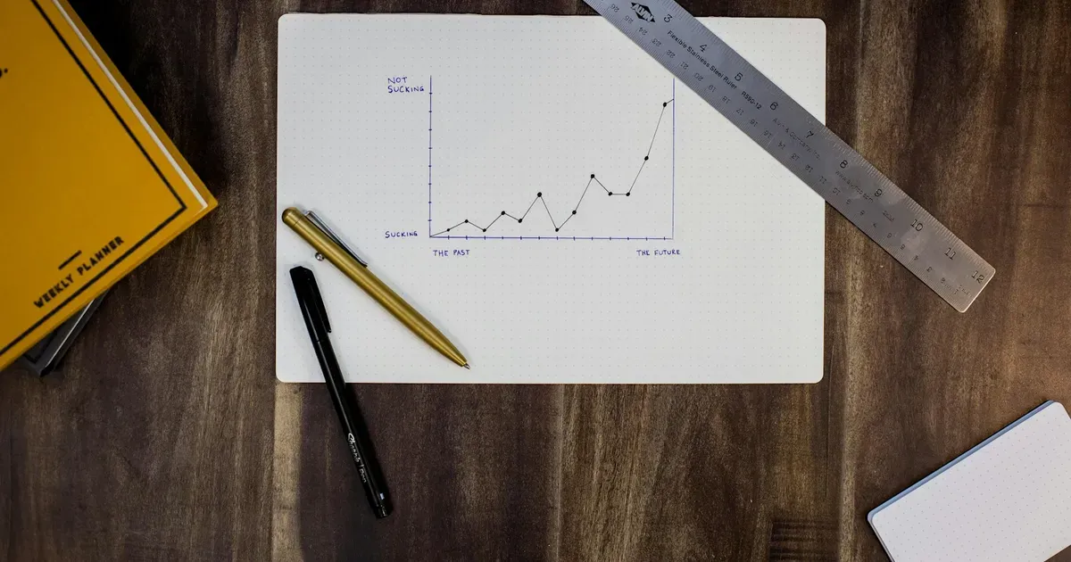 Gráfico de resultados desenhado em papel sobre uma mesa com canetas e régua, ilustrando como ler uma DRE