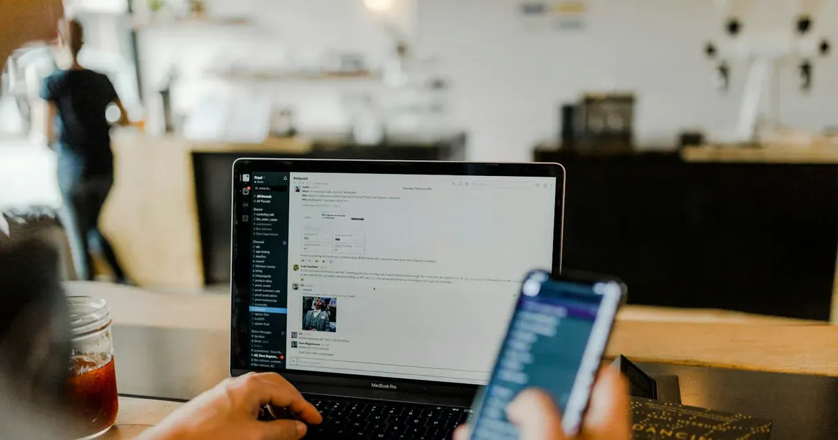 Pessoa usando o celular e o notebook ao mesmo tempo, representando extratos bancários que chegam ao sistema do BPO financeiro pelo Open Finance